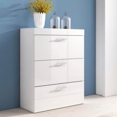 Móvel branco com três gavetas decorado com vaso de flores amarelas e frascos de vidro contra parede azul