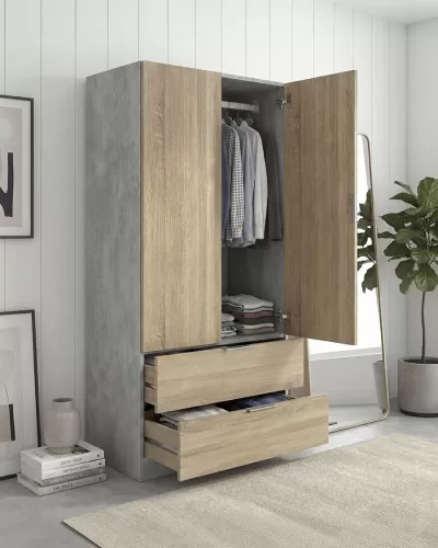 Roupeiro cinzento e madeira clara aberto com roupa pendurada e gavetas abertas em ambiente moderno com planta e espelho