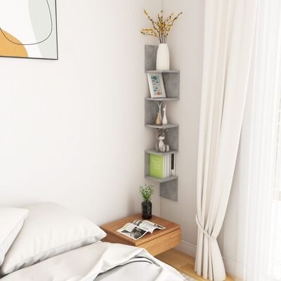 Estante de canto cinzenta com livros e objetos decorativos junto a cama e mesa de cabeceira em quarto branco
