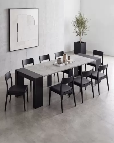 Mesa de jantar cinza com cadeiras pretas e vasos decorativos num ambiente minimalista