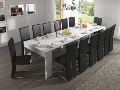 Mesa de jantar branca com 12 cadeiras pretas e utensílios de jantar brancos num ambiente com janela e decoração