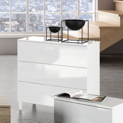 Cómoda branca de três gavetas com duas taças pretas em suportes metálicos