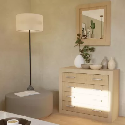 Cómoda de madeira clara com decoração e candeeiro de pé ao lado