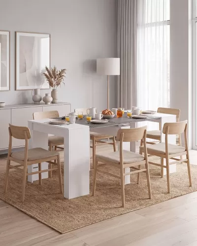 Mesa de jantar branca com seis cadeiras de madeira clara e estofado bege numa sala clara