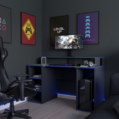 Área de gaming com escrivaninha preta iluminada a azul, monitor, cadeira preta e quadros de jogos na parede