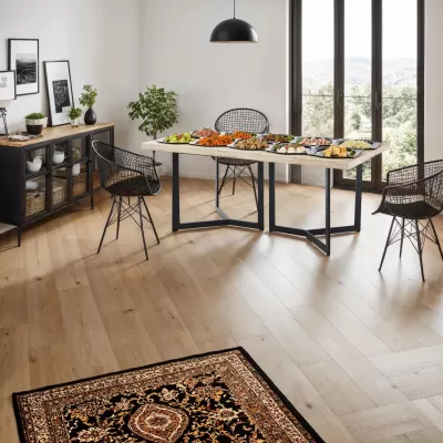 Sala de jantar moderna com mesa de madeira clara, cadeiras de metal pretas e buffet preto com decoração e pratos sobre a mesa.