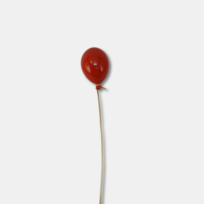 Balão vermelho amarrado a uma corda fina sobre fundo branco