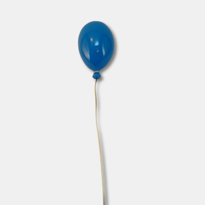 Balão azul suspenso por fita branca sobre fundo cinzento
