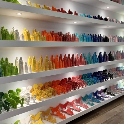 Figuras decorativas coloridas de cerâmica organizadas em prateleiras brancas