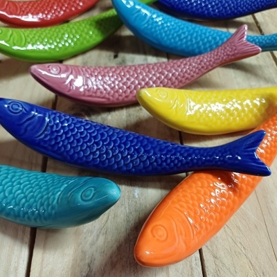 Peixes decorativos de cerâmica coloridos em superfície de madeira clara