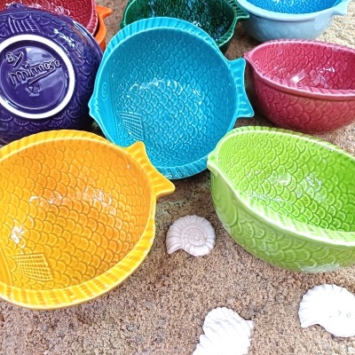 Tigelas de cerâmica coloridas em formato de peixe com padrão de escamas na areia