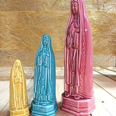Três estatuetas coloridas de Nossa Senhora de Fátima em cerâmica vidrada