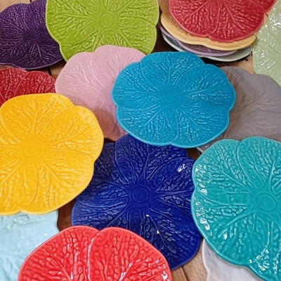 Placas cerâmicas coloridas com textura em forma de flor em várias cores sobre madeira clara.