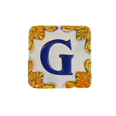 Azulejo cerâmico quadrado com a letra G azul e decoração amarela