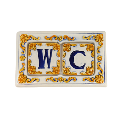Placa cerâmica decorativa branca com letras azuis WC e ornamentos amarelos