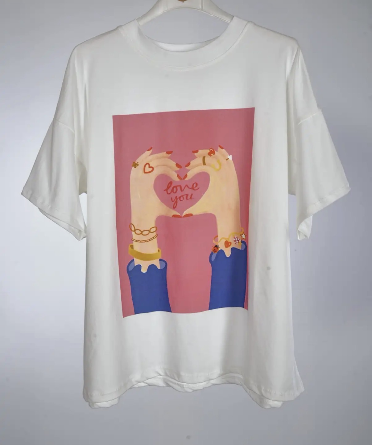 T-shirt branca com estampado de mãos formando coração e texto love you