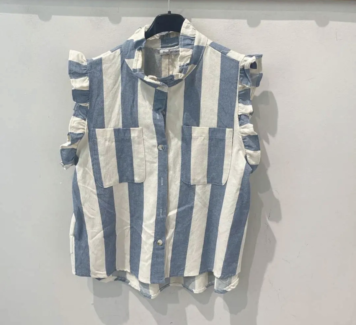 Blusa riscada azul e branca com folhos nas mangas pendurada