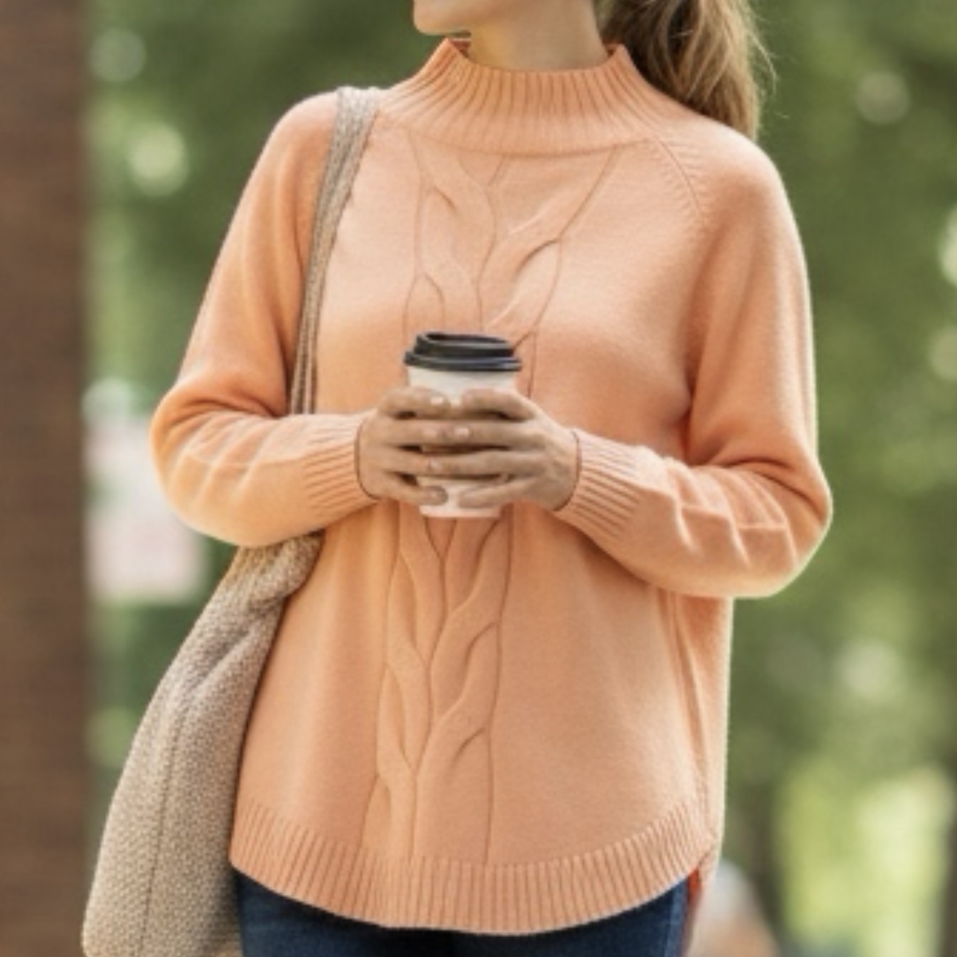 Suéter de malha cor de pêssego com gola alta e padrão trança, em ambiente exterior