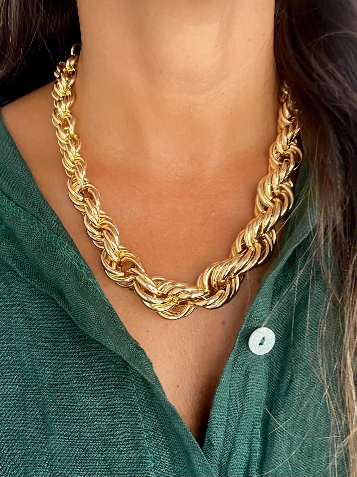 Colar dourado texturizado em pescoço com camisa verde