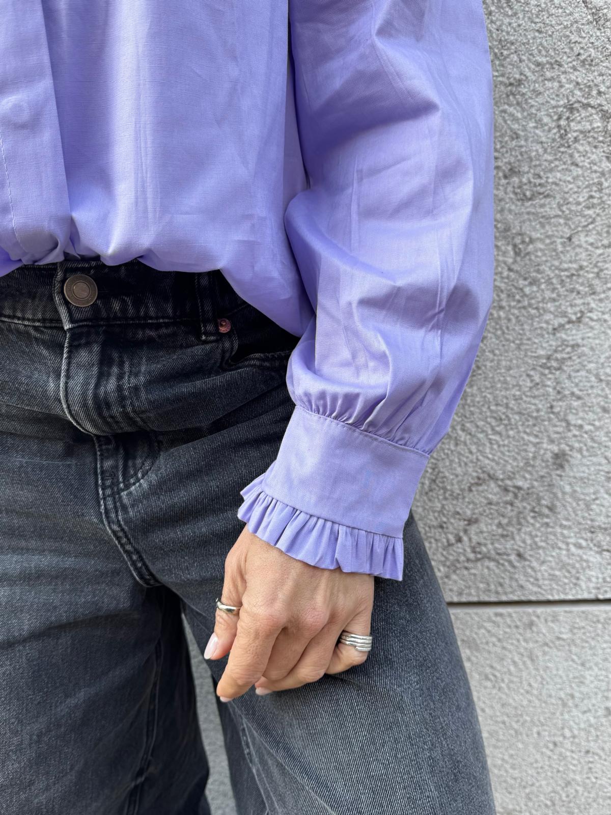 Camisa lilás com punhos franzidos e calças de ganga cinzentas