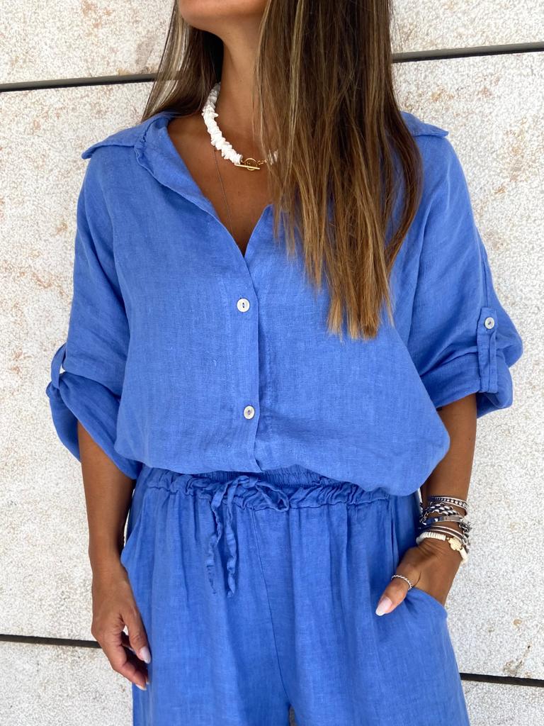 Mulher com conjunto azul de camisa e calças em tecido leve.