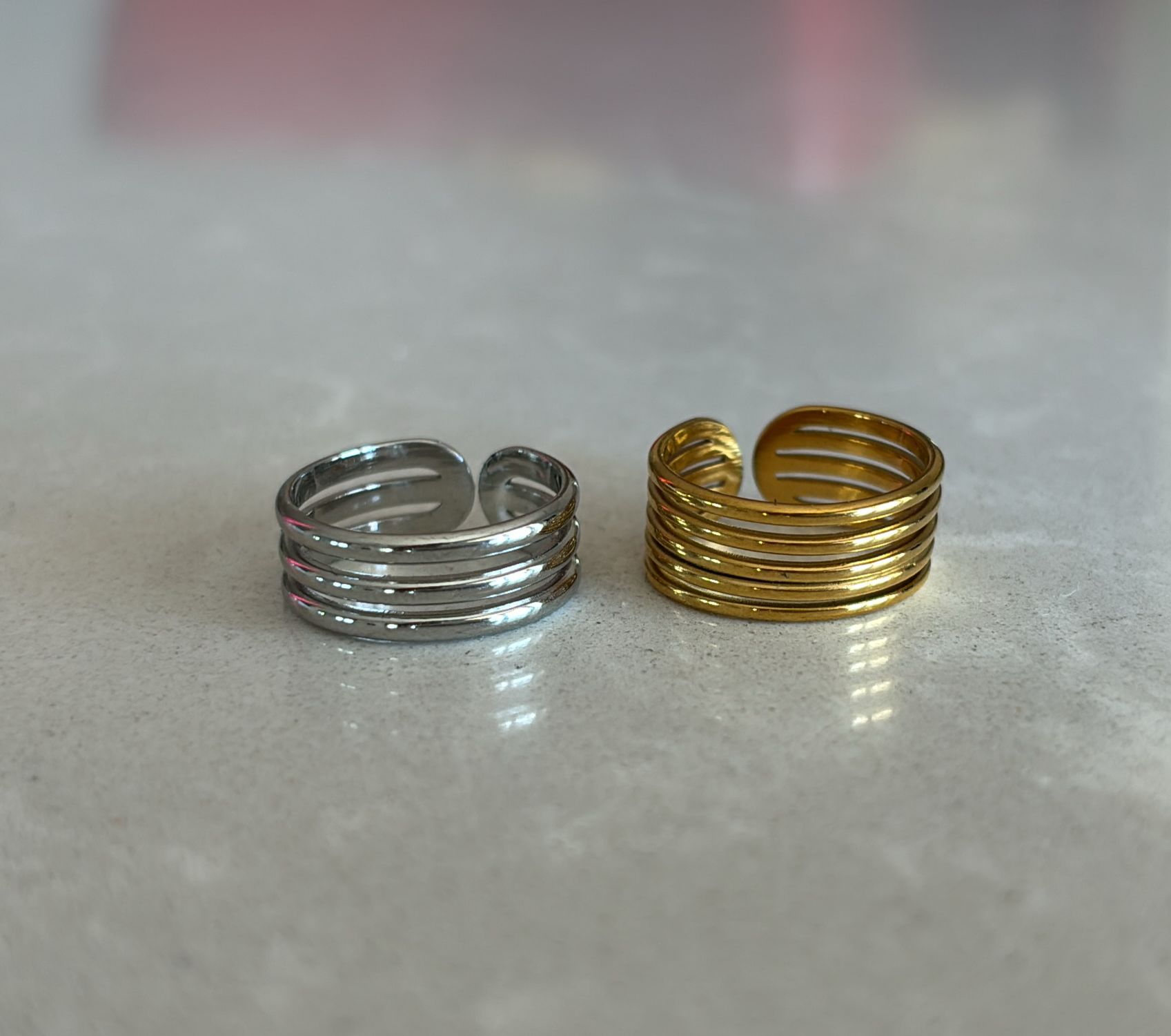 Dois anéis metálicos, um prateado e outro dourado, com bandas paralelas