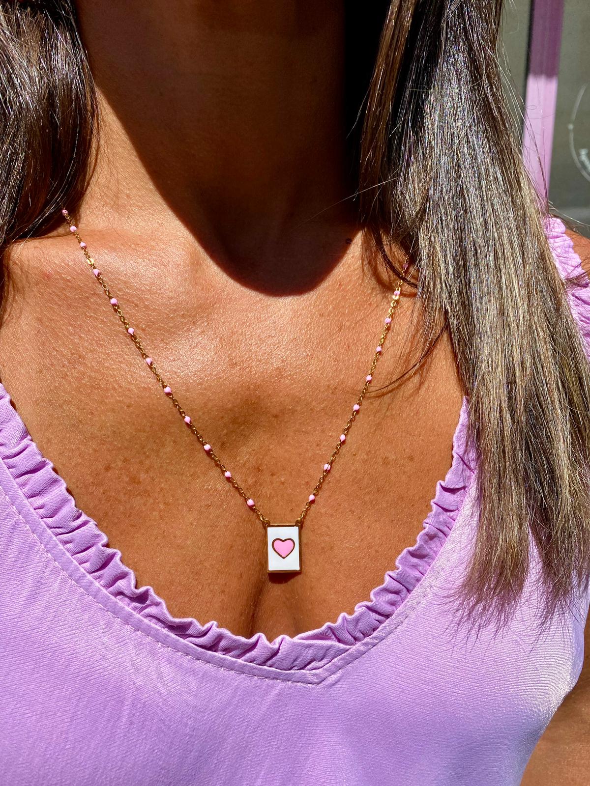 Colar delicado com pendente de coração rosa, usado com camiseta lilás