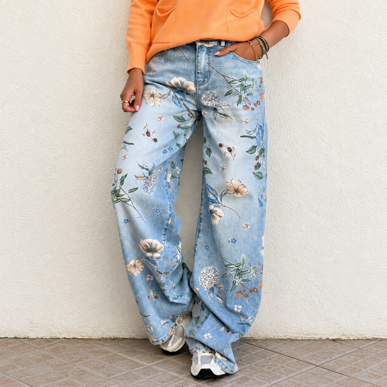Calças de ganga azul claro com padrão floral colorido e camisola laranja