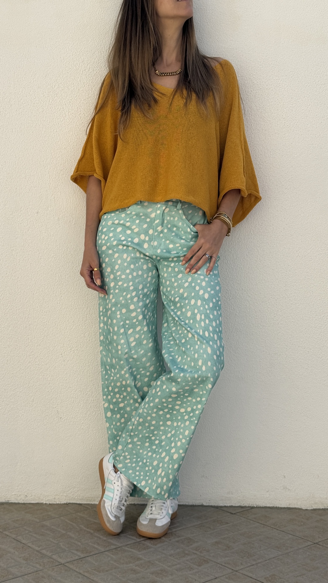 Mulher com blusa laranja e calças azuis com padrões brancos