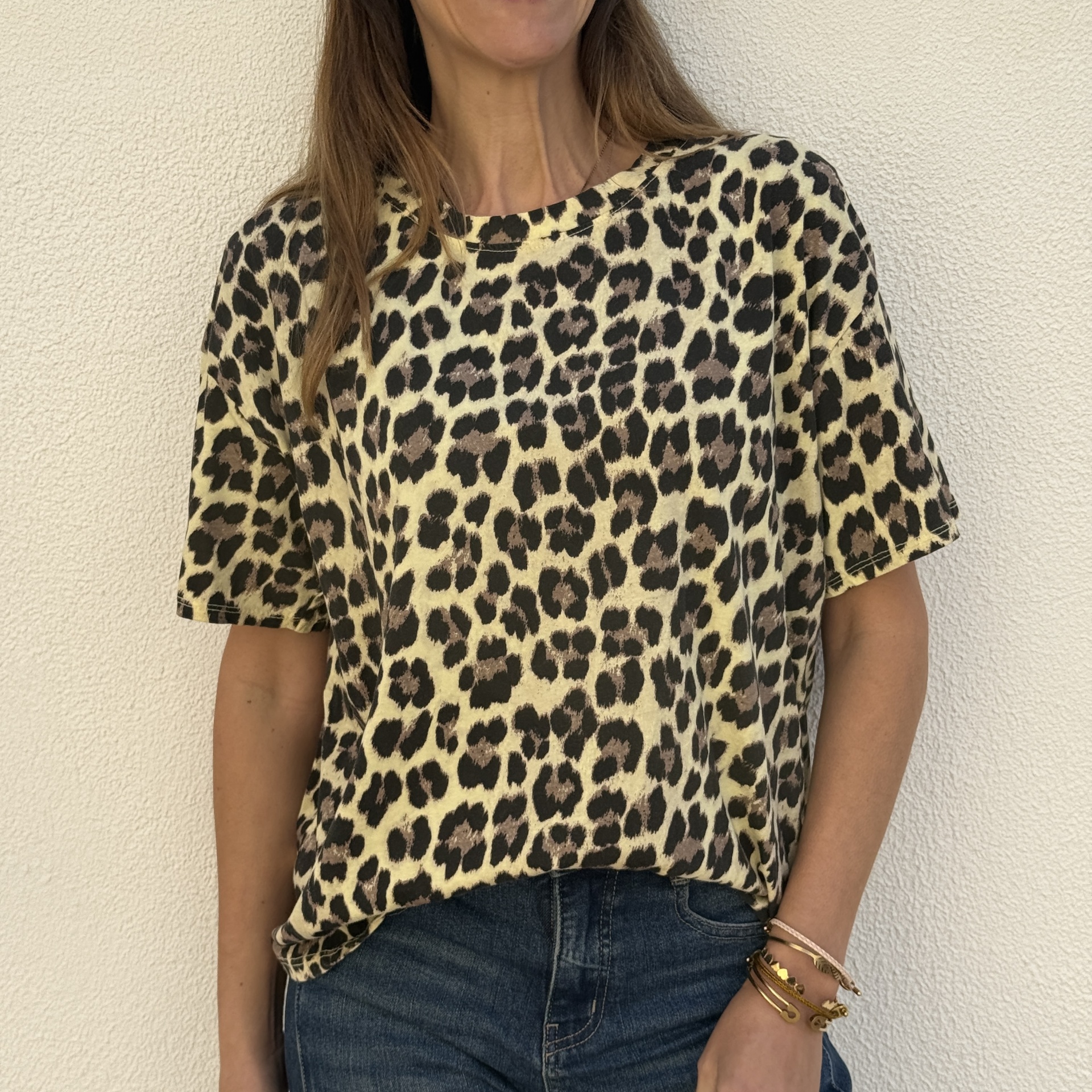 T-shirt de padrão animal print bege e preto, usada com calças de ganga azul.