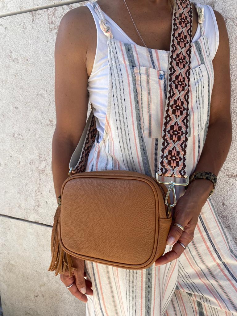 Bolsa castanha em pele com alça larga padrão geométrico usado com macacão riscas