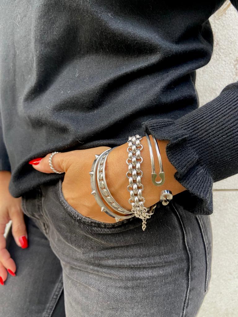 Braço com cinco pulseiras prateadas em roupa preta e unhas vermelhas