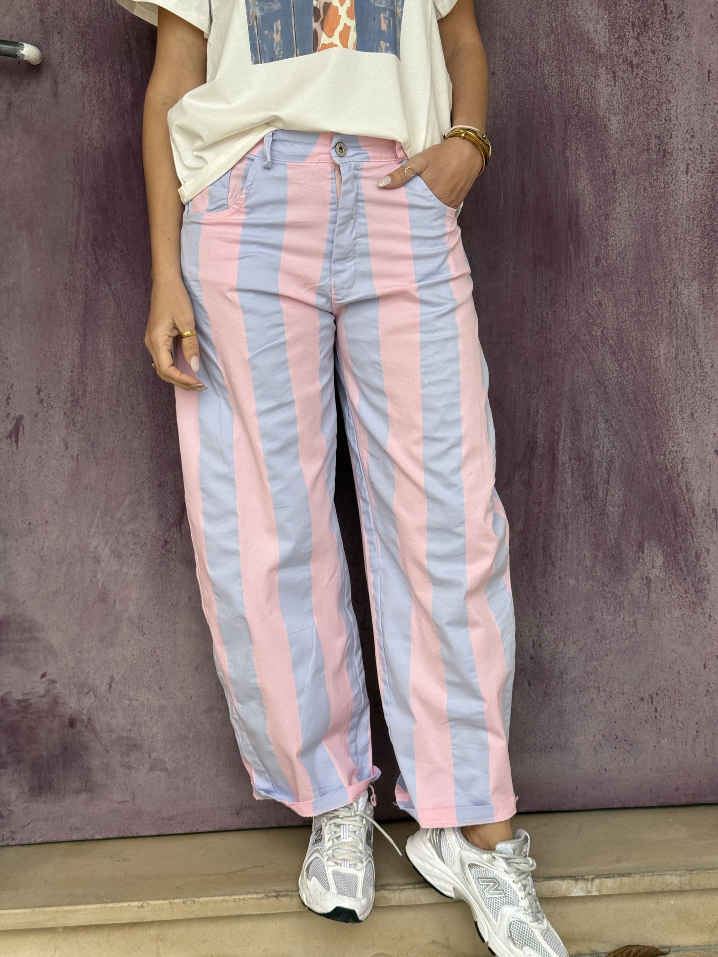 Calças com riscas largas rosa e azul claro, t-shirt branca, sapatilhas brancas