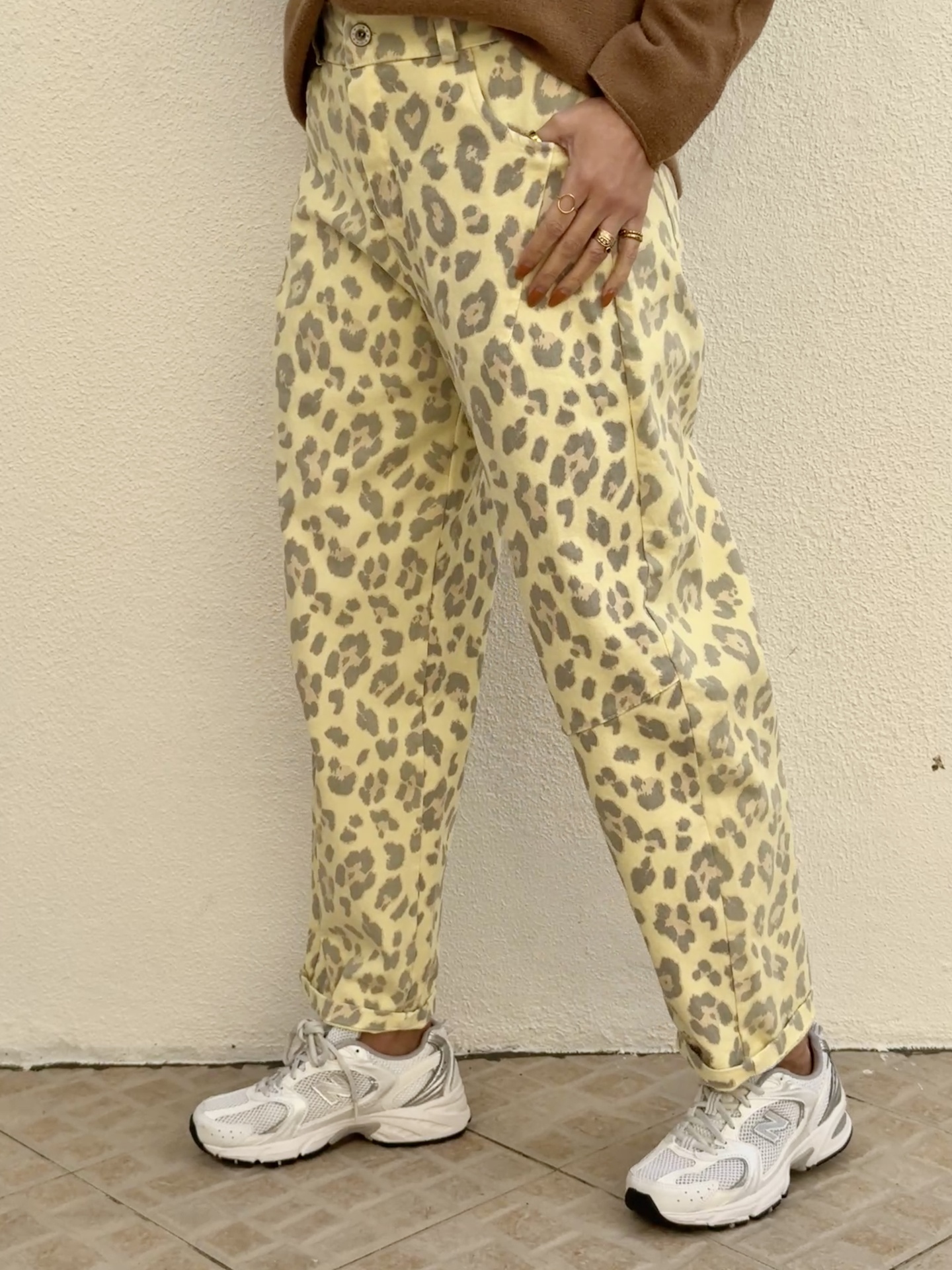 Calças padrão animal print amarelo e cinzento com sapatilhas brancas New Balance.