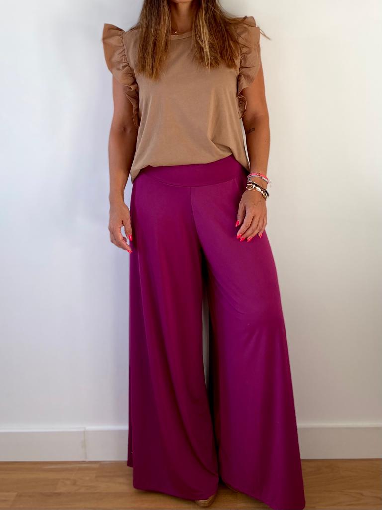 Conjunto de top bege com mangas franzidas e calças largas vinho em fundo branco.