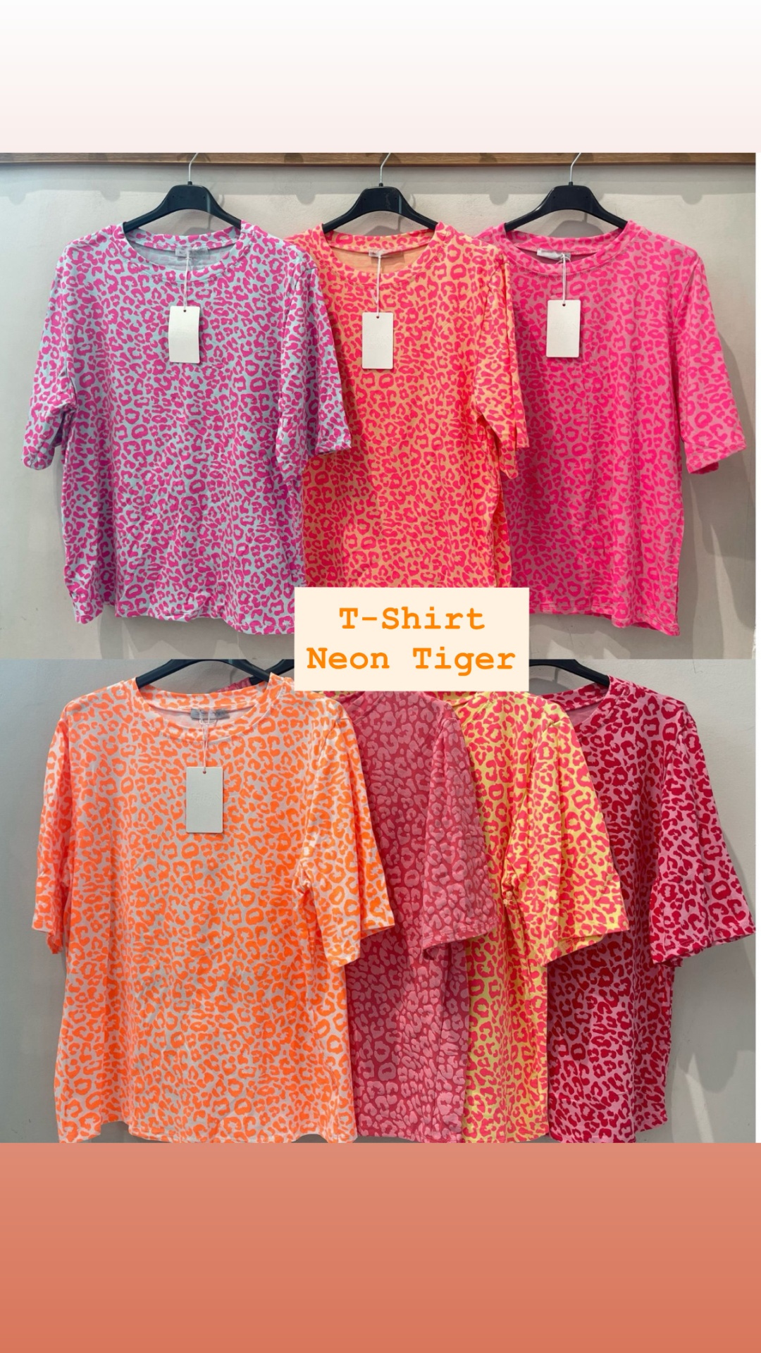 Sete t-shirts com padrão animal print em várias cores neon penduradas em cabides pretos