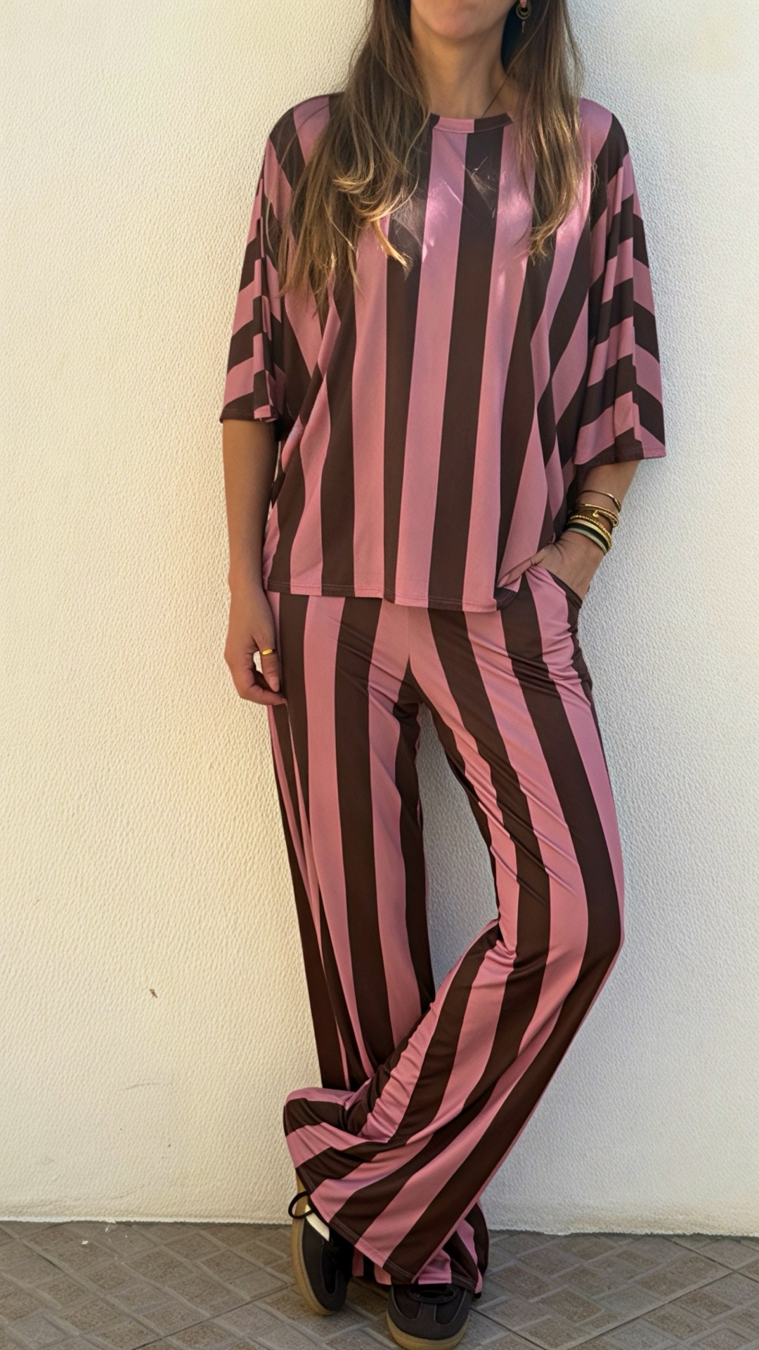Conjunto riscado rosa e castanho com túnica e calças usado por mulher.