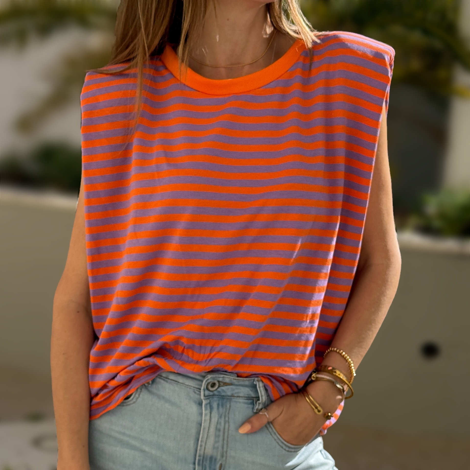 T-shirt sem mangas laranja e lilás com riscas horizontais, usada com calças de ganga claras