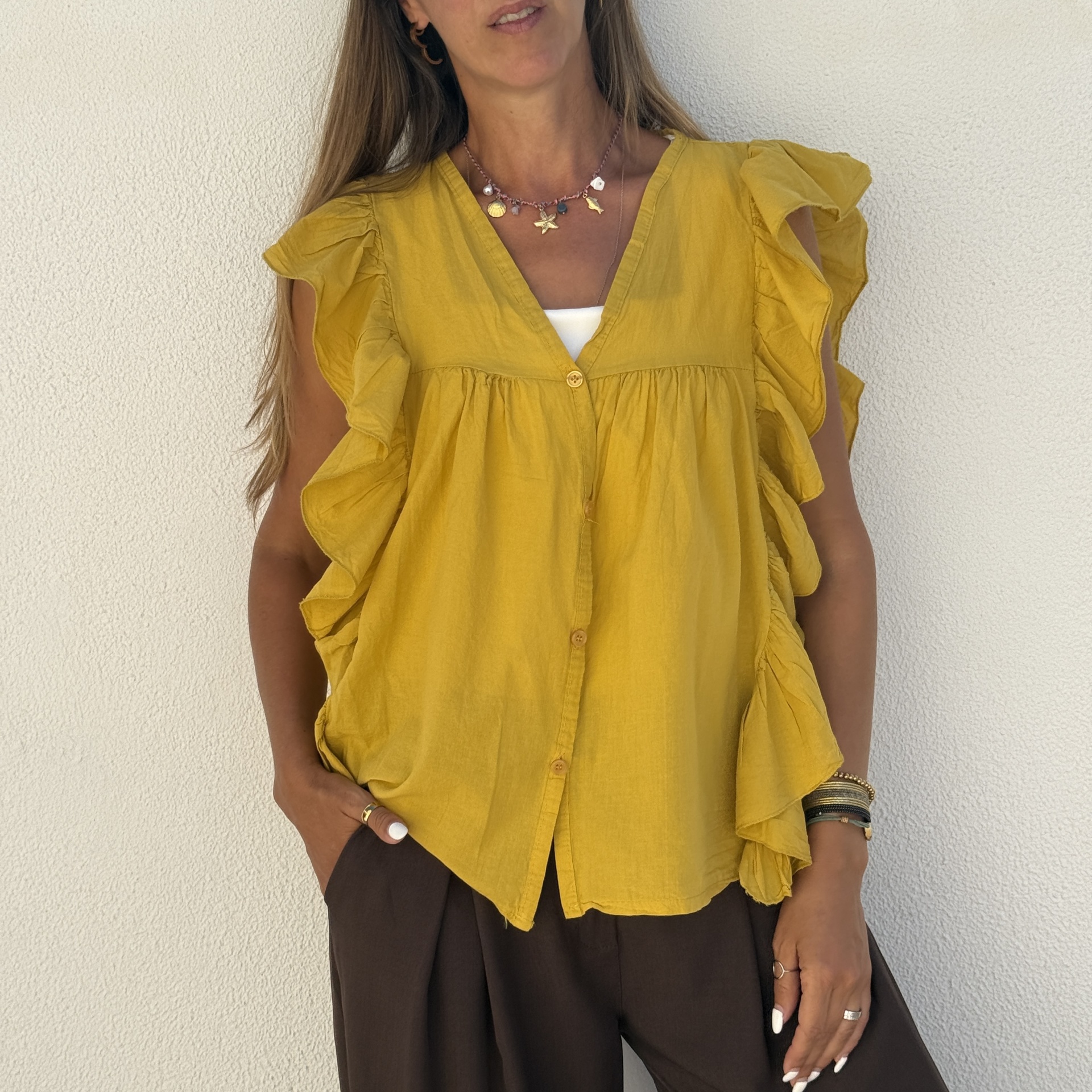 Blusa amarela com babados nas mangas e botões, com colar e pulseiras