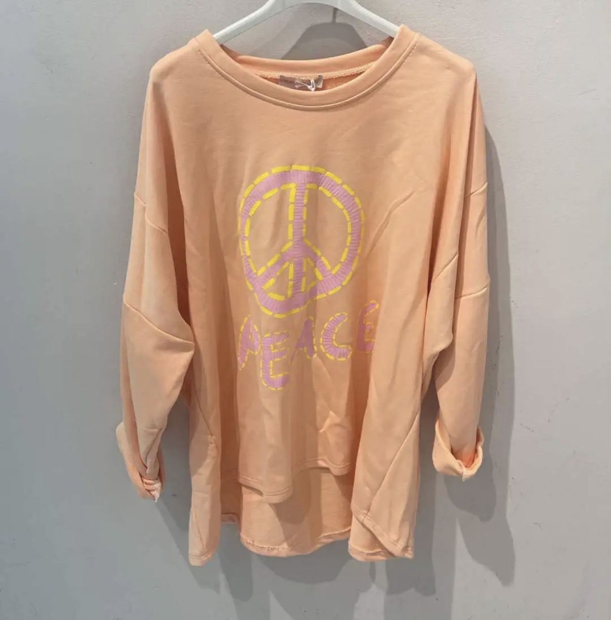 Sweatshirt cor de pêssego com símbolo da paz e palavra PEACE em rosa e amarelo