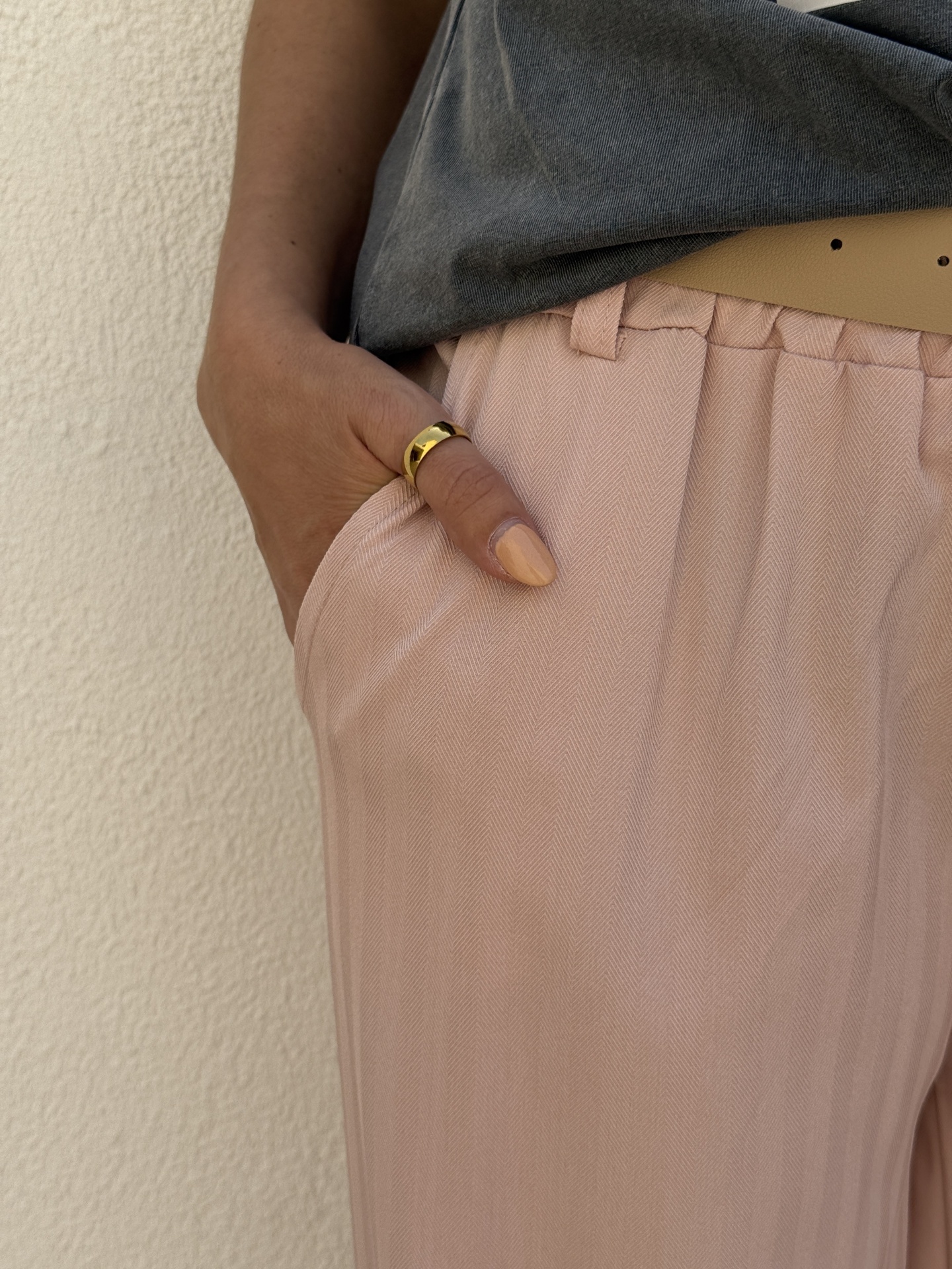 Calças rosas, cinto bege, t-shirt cinzenta, anel dourado e unhas cor pêssego