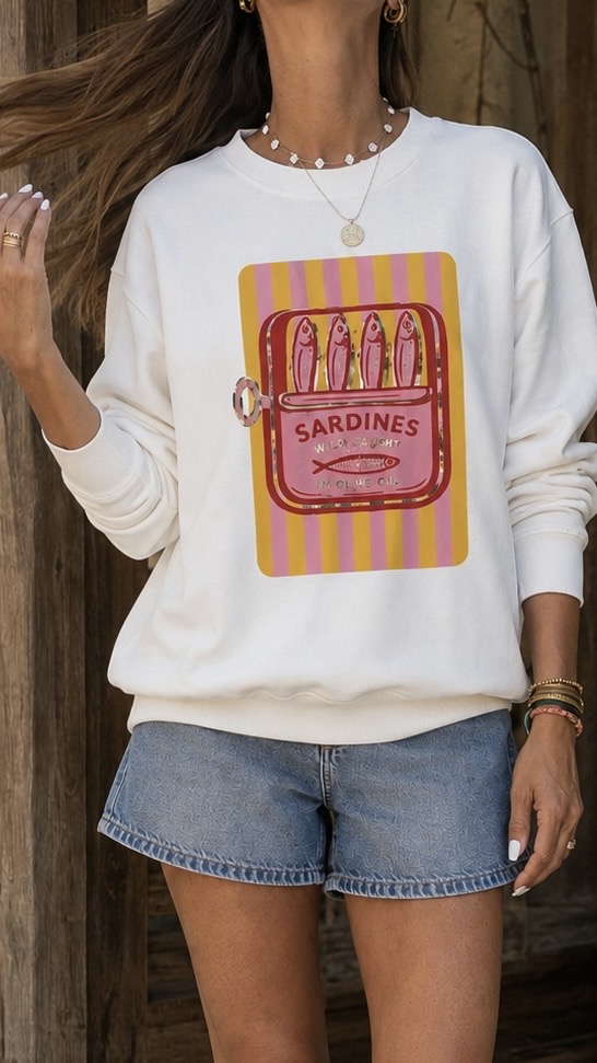 Sweatshirt branca com estampado colorido de lata de sardinhas e calções de ganga azuis.