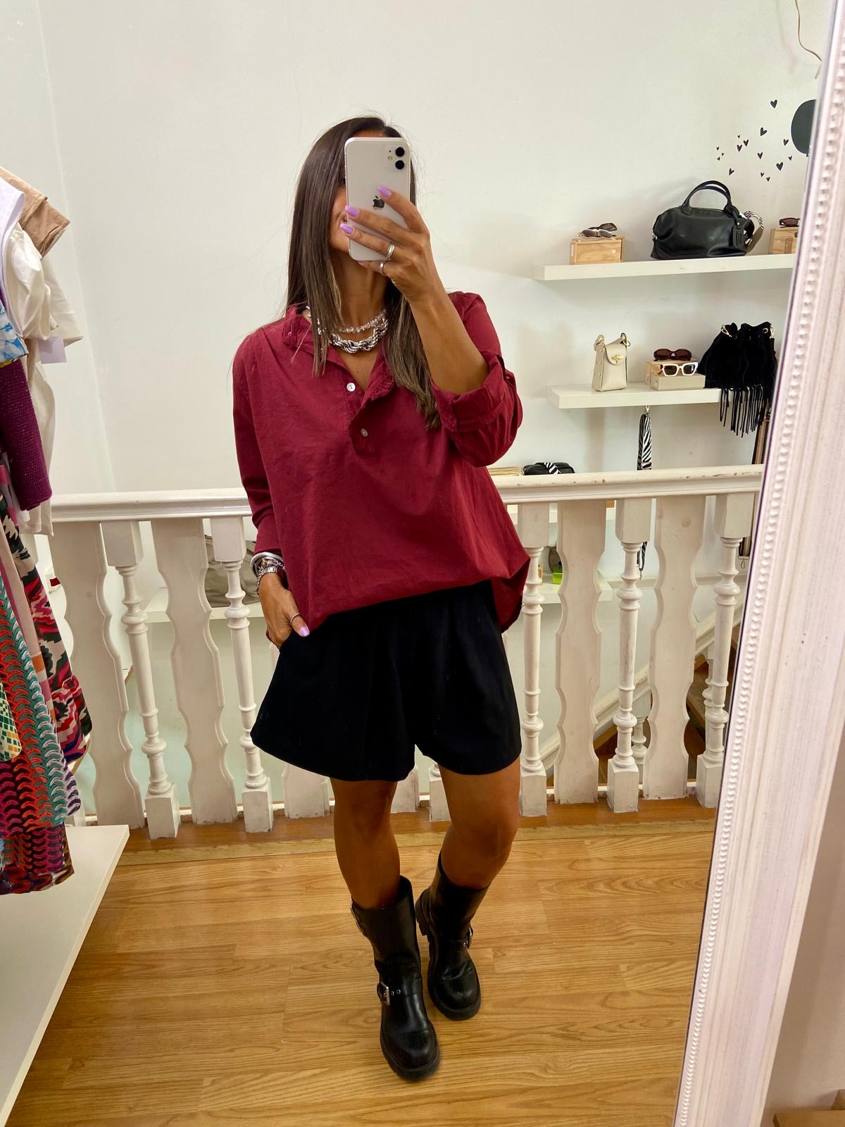 Pessoa vestindo camisa vermelha, calções pretos e botas pretas em loja