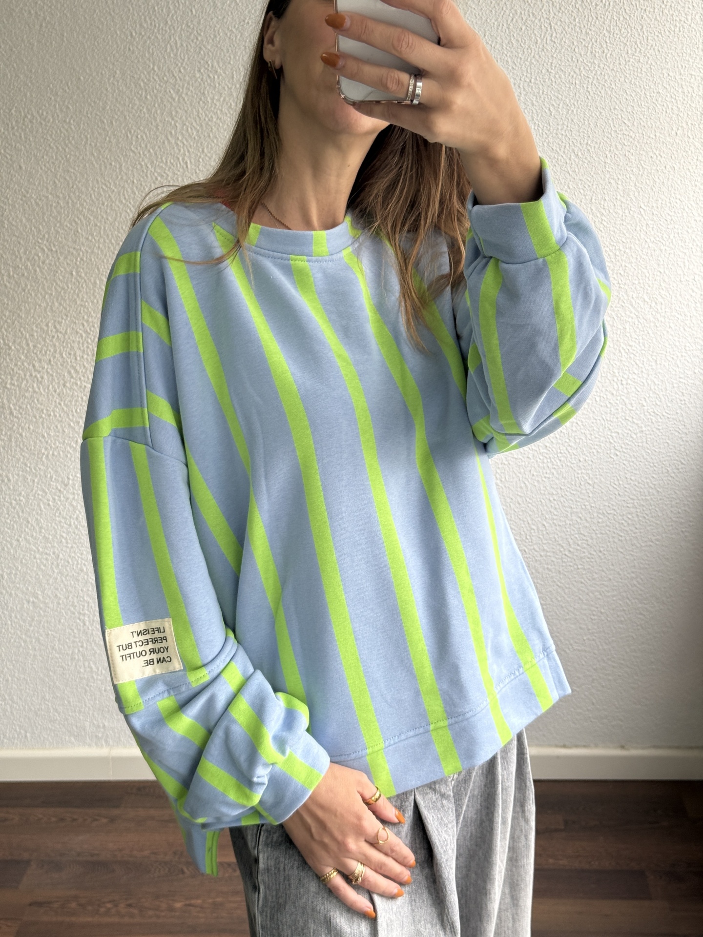 Sweatshirt azul claro com riscas verdes fluorescentes e etiqueta na manga