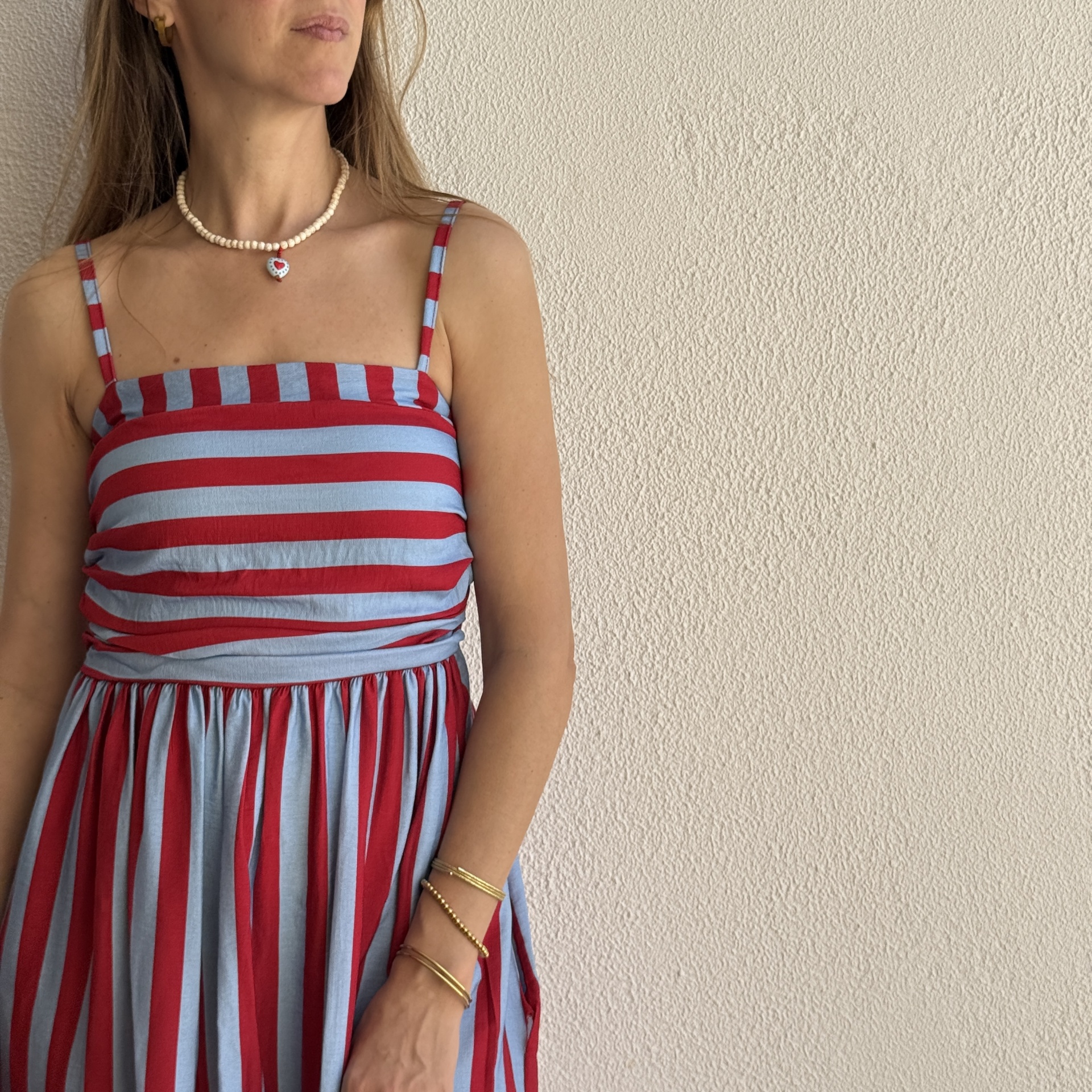 Vestido listrado vermelho e azul claro com alças finas e acessórios dourados