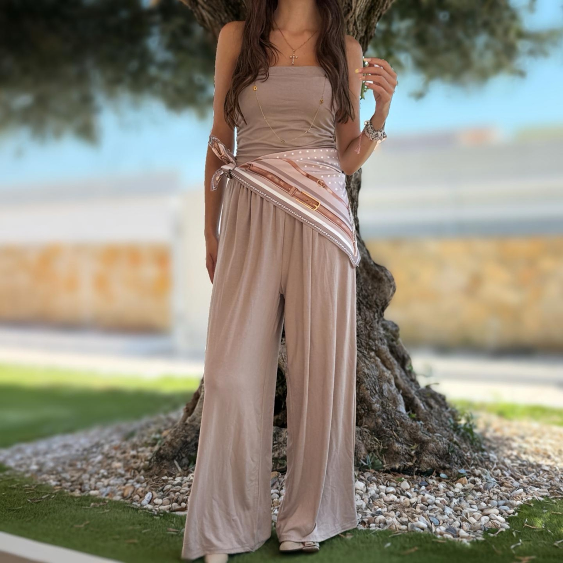 Conjunto feminino bege com lenço estampado e acessórios dourados ao ar livre