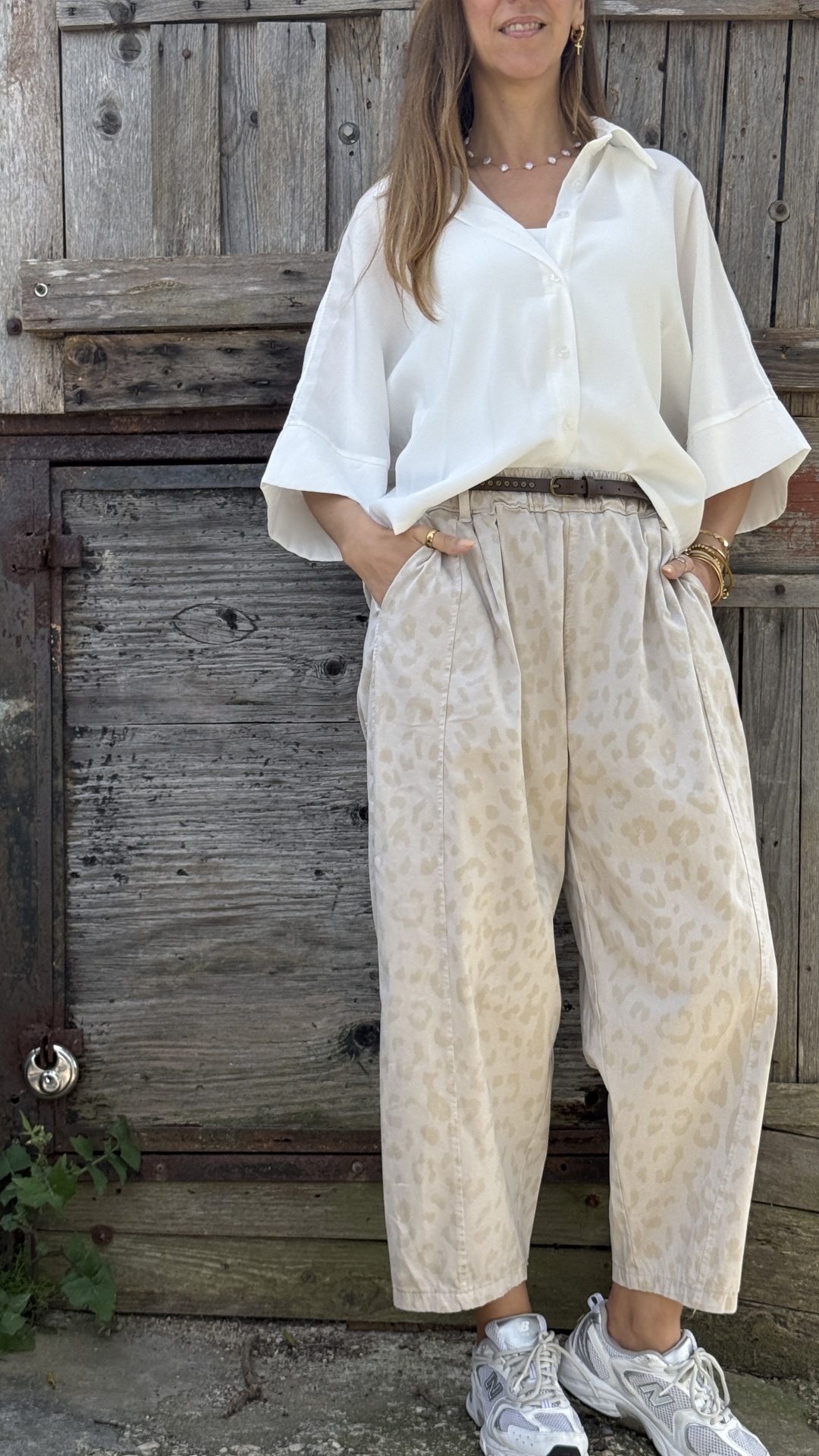 Calças largas bege padrão animal com cinto castanho e camisa branca com sapatilhas New Balance