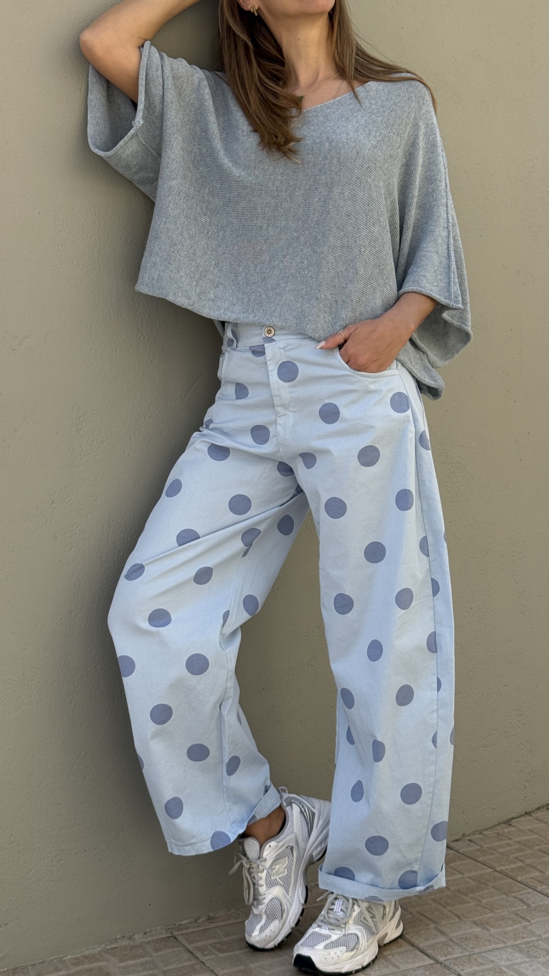 Calças largas azuis claras com bolinhas azuis escuras, top cinzento de malha e sapatilhas brancas
