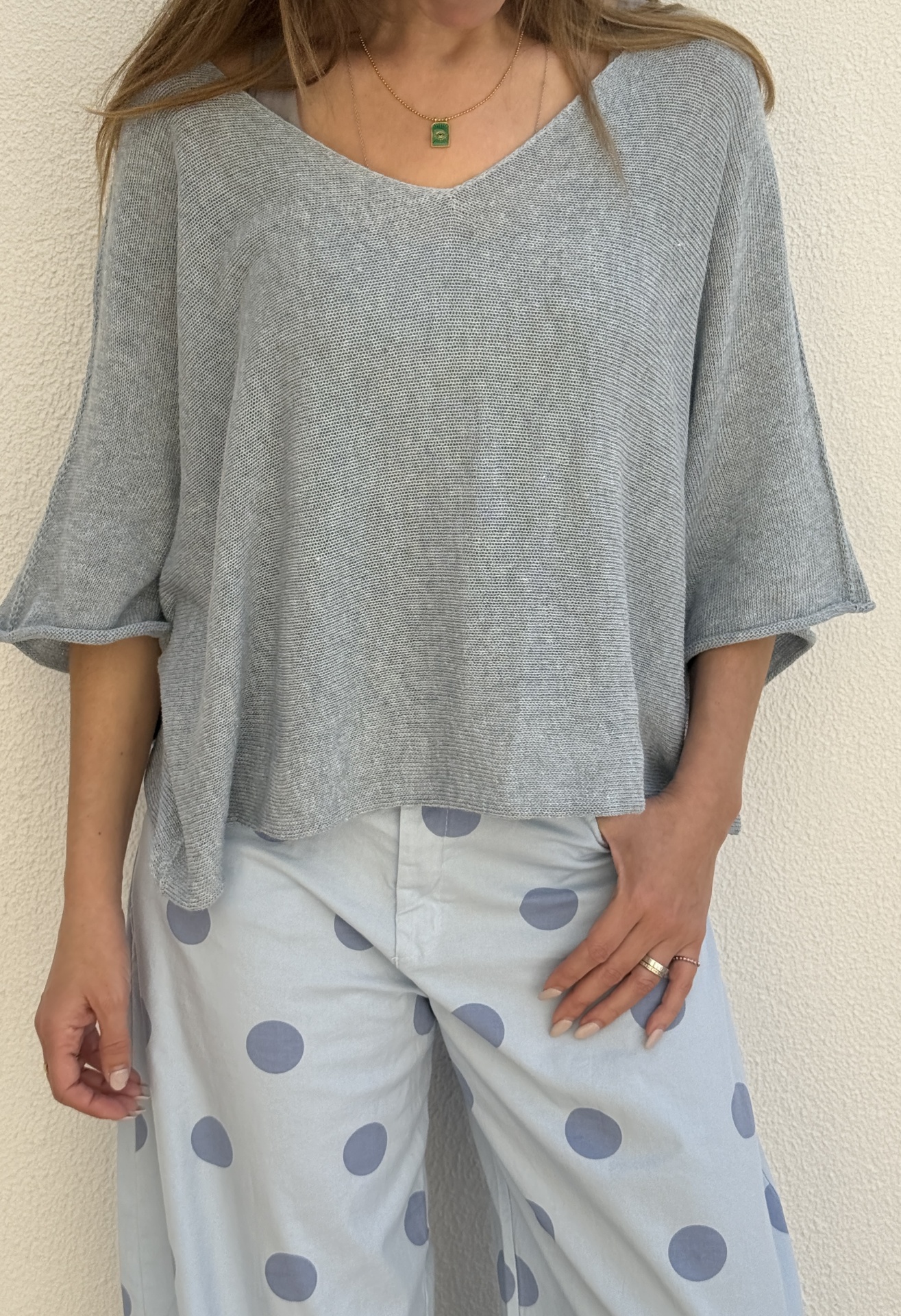 Conjunto de top cinzento de malha e calças azuis claras com bolas grandes azuis.