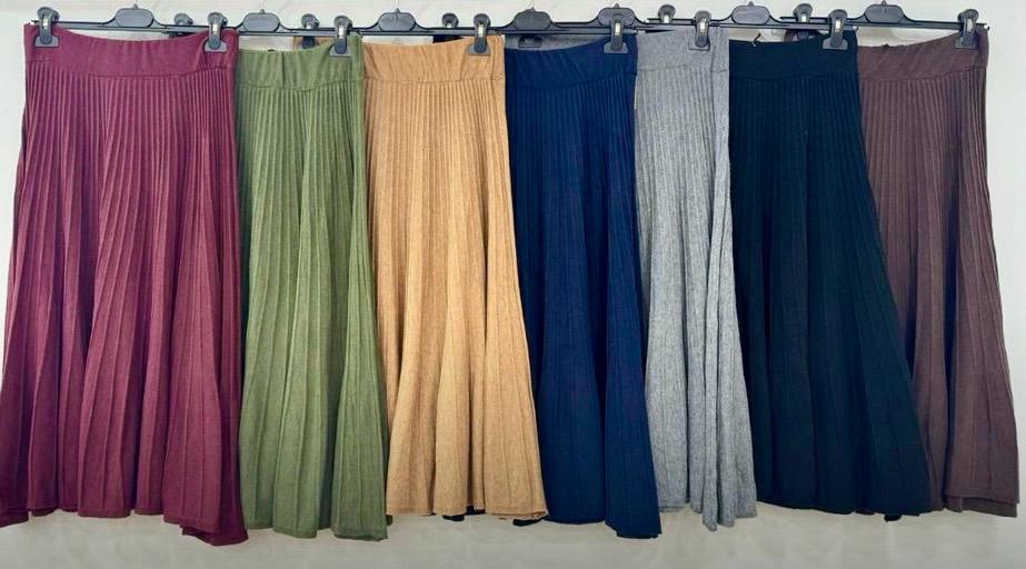 Saias plissadas coloridas penduradas em cabides contra parede branca